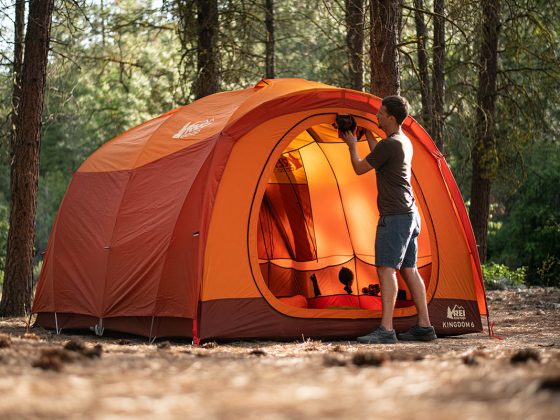 man starting to pack up his orange dome tent